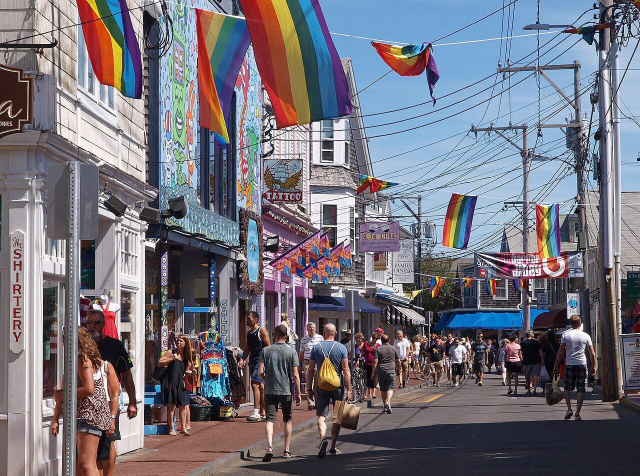 People walking along Commercial Street beneath rainbow flags in Provincetown